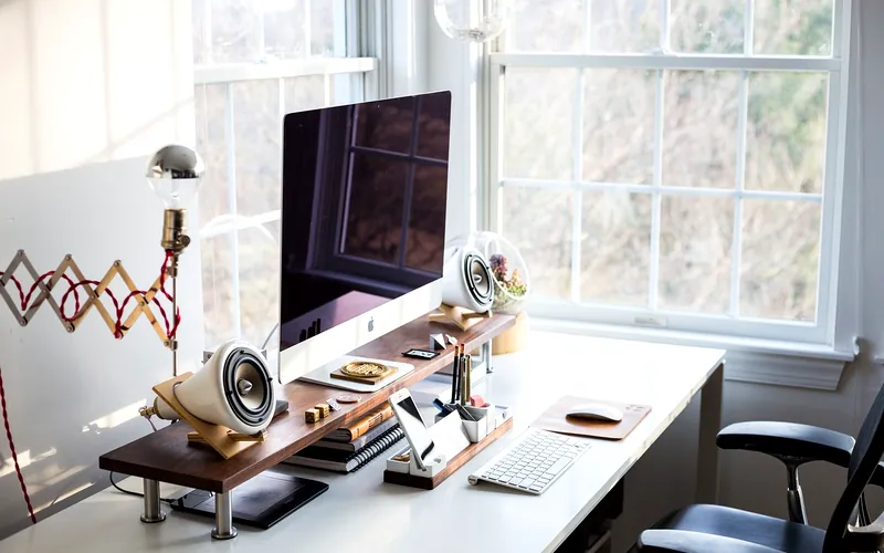 iMac monitor raised on a wooden desk riser — a properly elevated ergonomic workstation